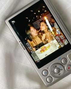 an old cell phone with two girls on it's screen and a candle in the background