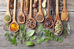 wooden spoons filled with different types of spices and herbs on top of a table