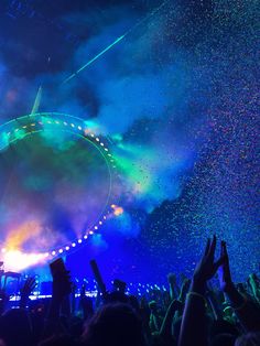 a large crowd at a concert with confetti in the air and lights on