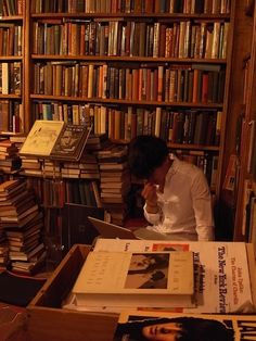 a man sitting at a desk in front of a book shelf filled with books and papers