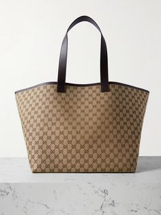 Gucci's 'Super' tote is exceptionally roomy, so you'll turn to it for weekend getaways and shopping trips. Made from coated-canvas printed all-over with the 'GG' monogram, it has leather trims and red and green stripes along the interior. There's enough space inside for your water bottle, laptop and spare flats, and the attached pouch keeps your cards and keys secure. Gucci Coated Canvas Tote Bag, Gucci Canvas Shopping Bag, Gucci Coated Canvas Travel Bag, Gucci Coated Canvas Everyday Bag, Gucci Coated Canvas Bags, Everyday Gucci Coated Canvas Bag, Designer Tote Bag With Lined Interior, Luxury Tote Bag With Lined Interior, Designer Travel Bag With Lined Interior