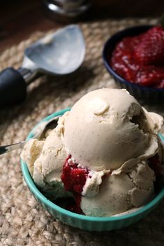 a bowl filled with ice cream and strawberries next to spoons on a table