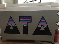 a cooler sitting on top of a hard wood floor next to a wall with mountains painted on it