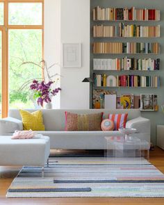 a living room filled with lots of furniture and bookshelves next to a window