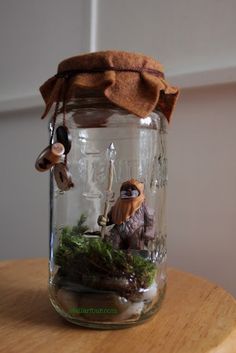 a glass jar filled with miniature figurines on top of a wooden table