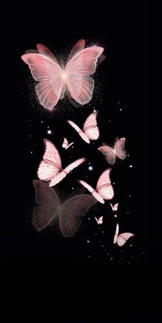 some pink butterflies flying in the air with their wings spread out and glowing at night