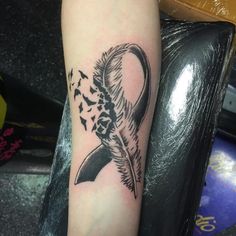 a black and white tattoo on the arm of a person with a feather in it