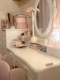 a white vanity with pink chairs and a round mirror