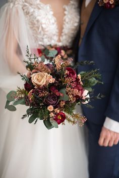 the bride and groom are holding their bouquets in their hands while they stand close together