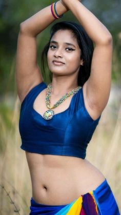 a woman in a blue top and multicolored skirt is posing for the camera