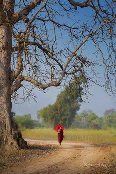 a painting of a woman walking down a dirt road with an umbrella over her head