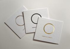 three white cards with gold rings on them