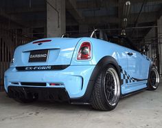 the rear end of a blue car parked in a garage