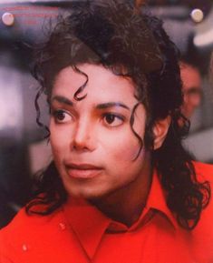 a man with curly hair wearing a red shirt