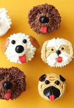 cupcakes made to look like dogs and sheep are on a yellow tablecloth