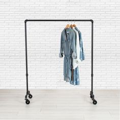 a clothes rack with two shirts hanging on it's sides and three black wheels