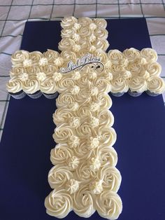 a cross made out of cupcakes sitting on top of a blue table cloth