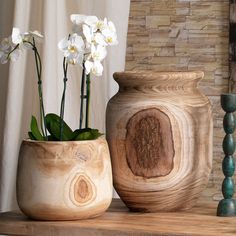 two vases with flowers in them sitting on a shelf