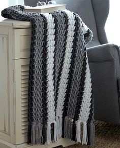 a black and white crocheted blanket sitting on top of a table next to a chair