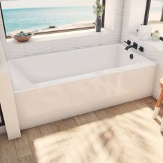 a large white bath tub sitting next to a window in a room with wooden floors