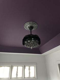 a chandelier hanging from the ceiling in a room with purple walls and white trim