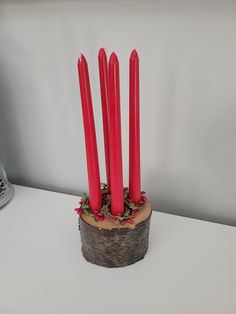 four red candles sitting on top of a piece of wood