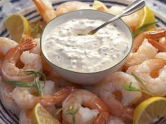 a plate topped with shrimp and dip surrounded by lemon wedges, garnished with parsley