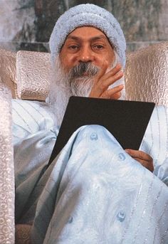 an old man sitting in a chair holding a book