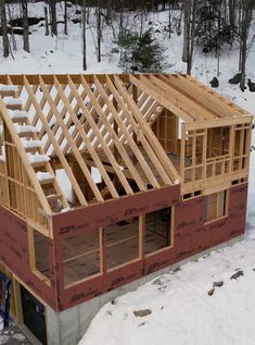 a house being built in the snow with wooden framing on it's roof and windows