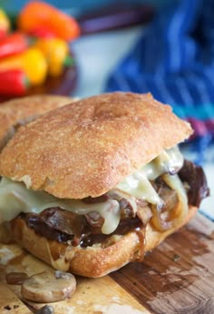 a close up of a sandwich on a wooden cutting board with mushrooms and melted cheese