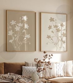 a living room filled with furniture and two paintings on the wall above each couches