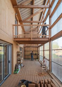 two men are standing on the upper level of a building with wood floors and windows