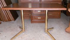 a wooden desk with two metal legs in front of drawers and other wood furniture behind it