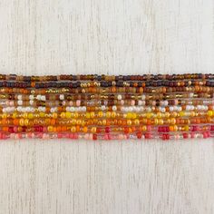 multicolored glass beads are lined up on a white surface with a wooden background