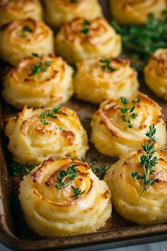 there are many small rolls on the baking sheet with some garnish sprinkled on top