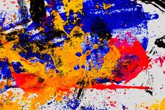 an abstract painting with yellow, blue and red paint splattered on the surface