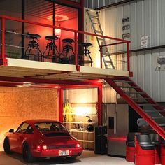 a red car parked in front of a garage with stairs leading up to the second floor