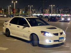 a white car parked in a parking lot at night