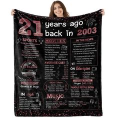 a woman holding up a black and pink poster that says 21 years ago back in 2003