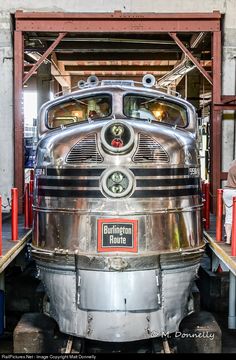 the back end of an old train car in a garage with people looking at it