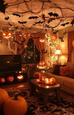 a living room decorated for halloween with pumpkins on the ceiling and bats hanging from the ceiling