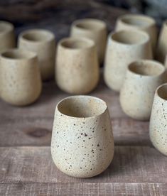 several white vases sitting on top of a wooden table next to eachother