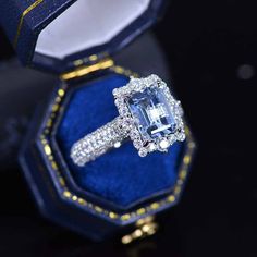 an engagement ring in a blue velvet box with gold trimmings and diamond accents