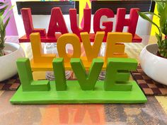 the letters laugh, laugh, laugh and laugh on top of each other in front of some potted plants