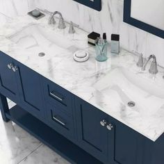 two sinks and mirrors in a bathroom with marble counter tops, blue cabinets and white walls