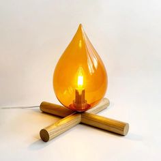 an orange glass lamp sitting on top of two wooden dows next to a light bulb