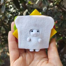 someone is holding up a small piece of felt that looks like a toaster with a face on it