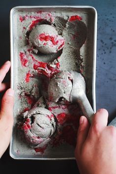 a person is scooping out some ice cream from a metal pan with red sprinkles