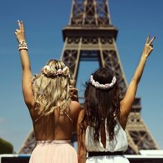 two women standing in front of the eiffel tower with their arms up and hands raised