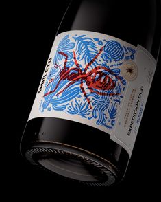 a bottle of red wine with a blue and red design on the label is photographed against a black background